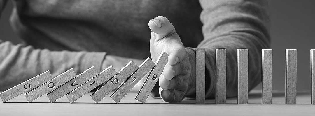 A hand extends in he middle of a row of dominoes to keep the rest from falling.