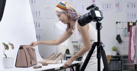 A business owner takes photos of a designer purse in her studio