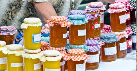 A vendor puts out her jams and jellies on display in a food booth.